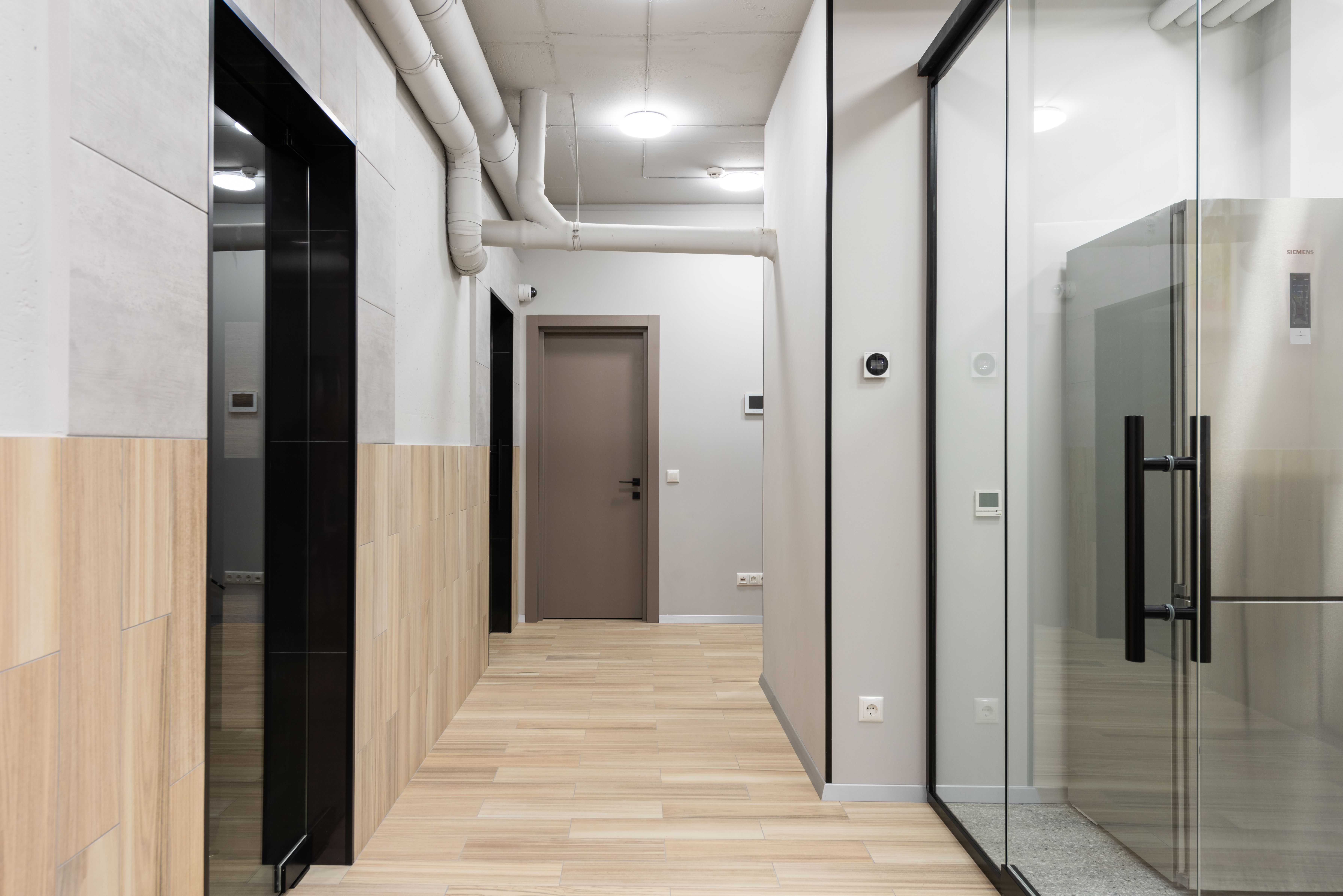 Modern interior of corridor with glass doors and parquet floor in contemporary workplace