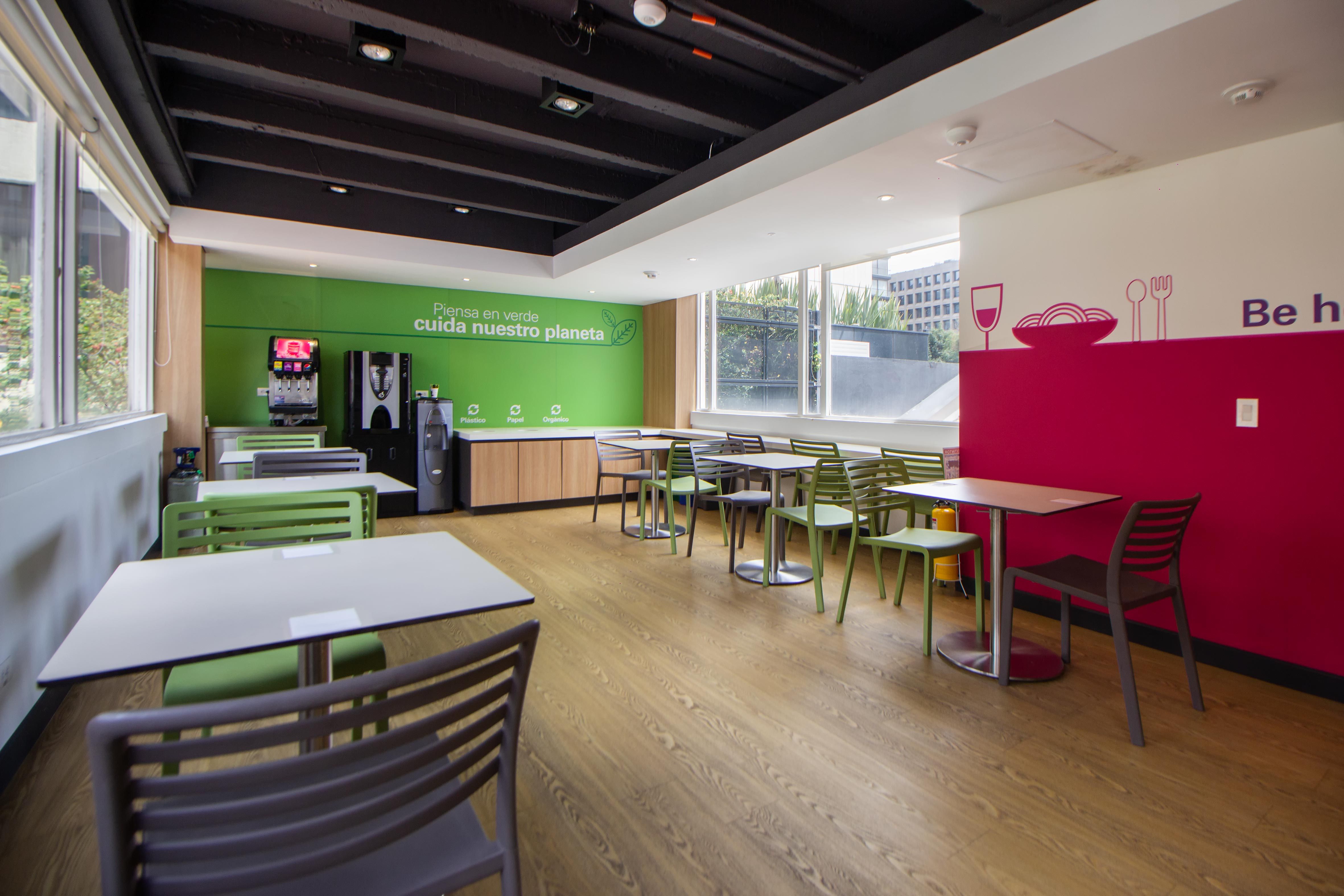 Spacious cafeteria with a minimalist design, featuring colorful chairs and tables, ready for dining.