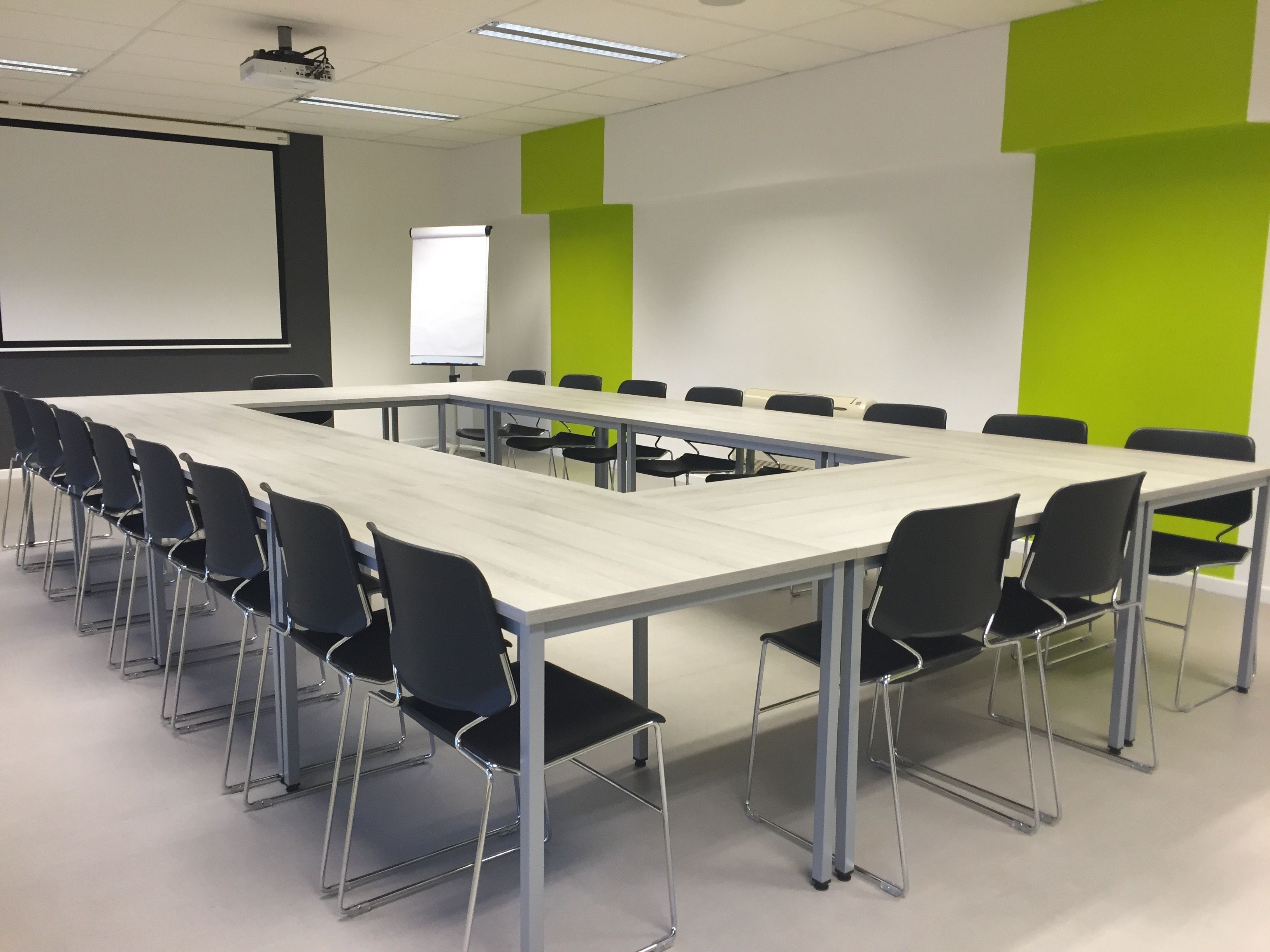Bright and modern conference room with U-shaped table setup, perfect for meetings and presentations.