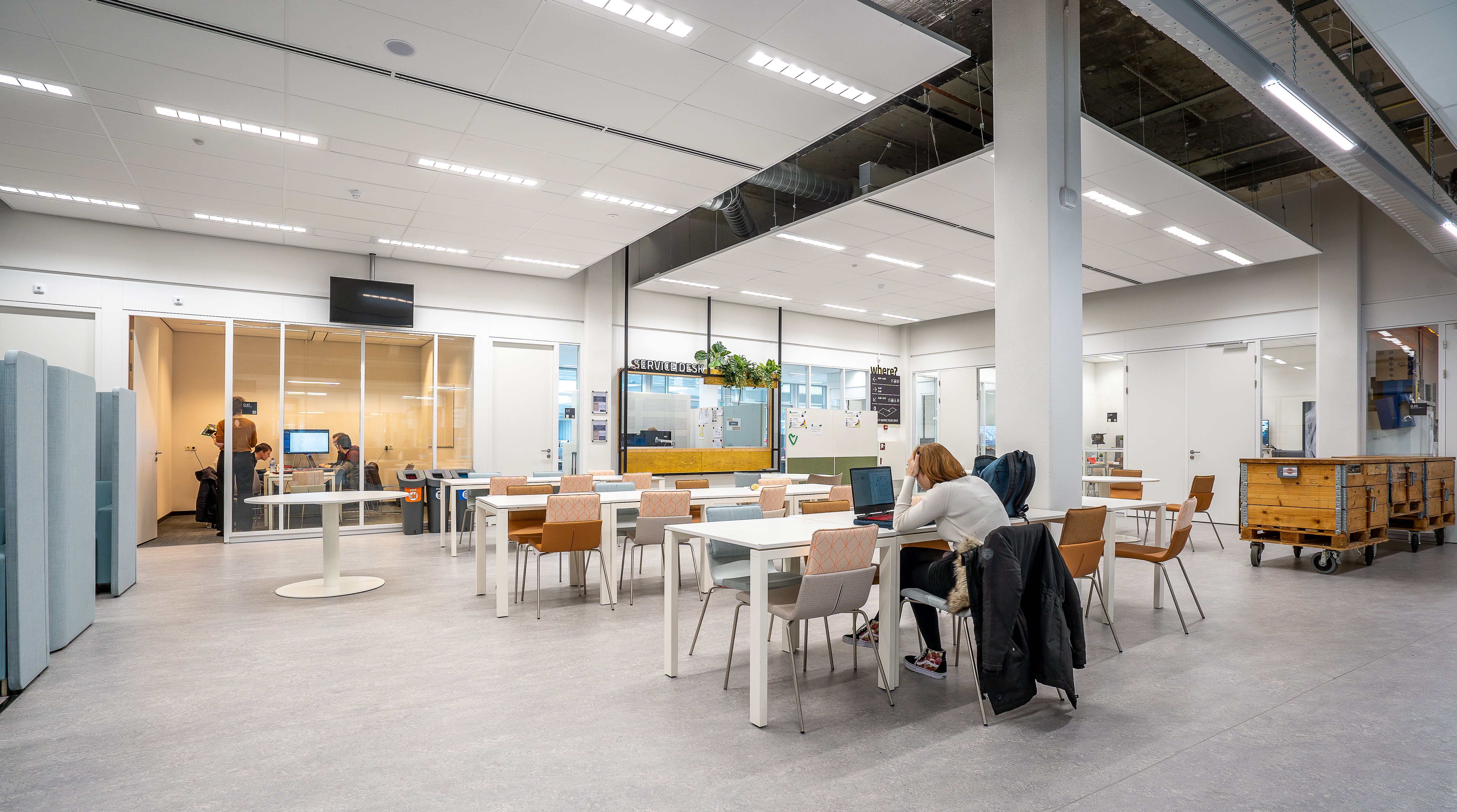 A spacious and modern office cafeteria with tables, seating, and a collaborative workspace.