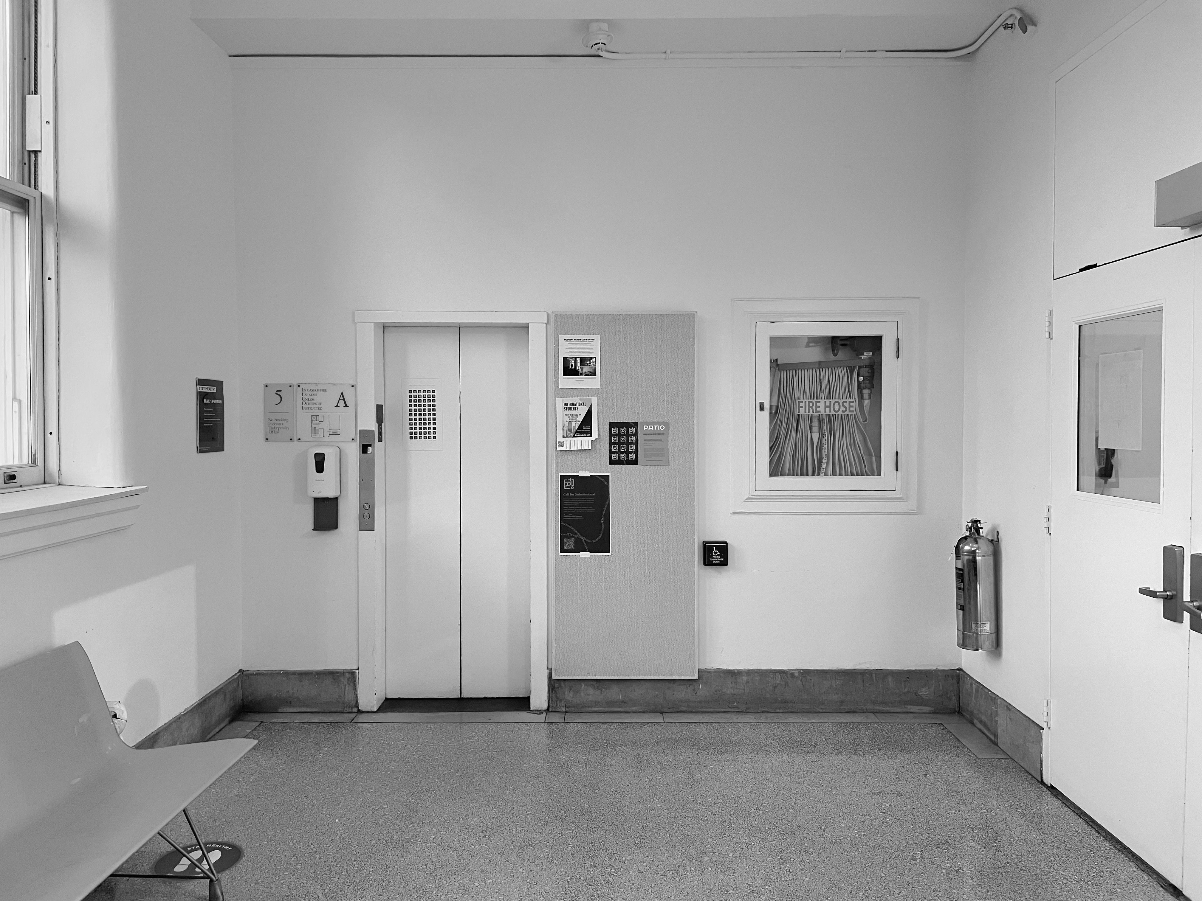 A minimalist black and white space featuring an elevator and seating area.