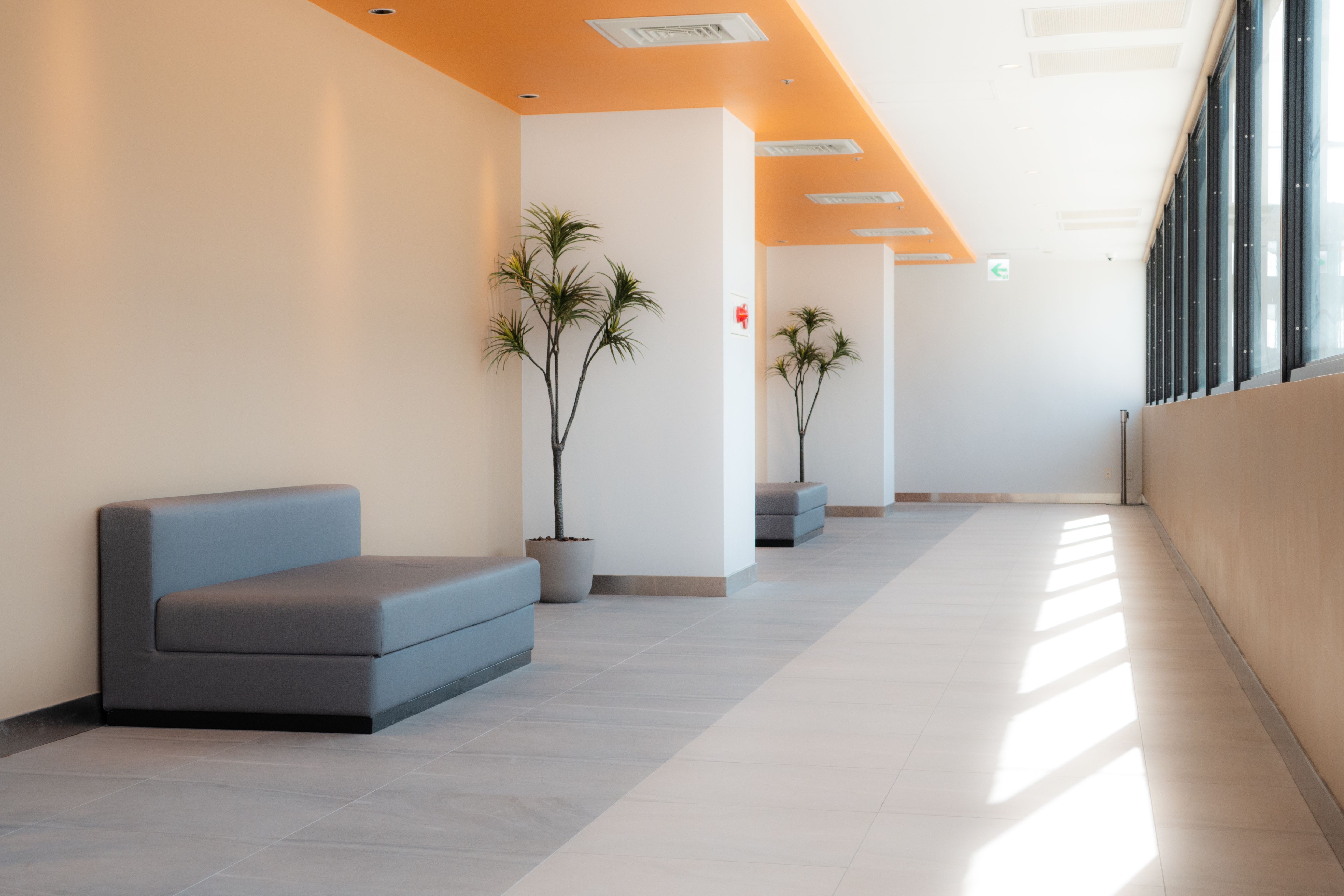 A bright, modern hallway in a Taiwanese building featuring minimalist seating and natural light.
