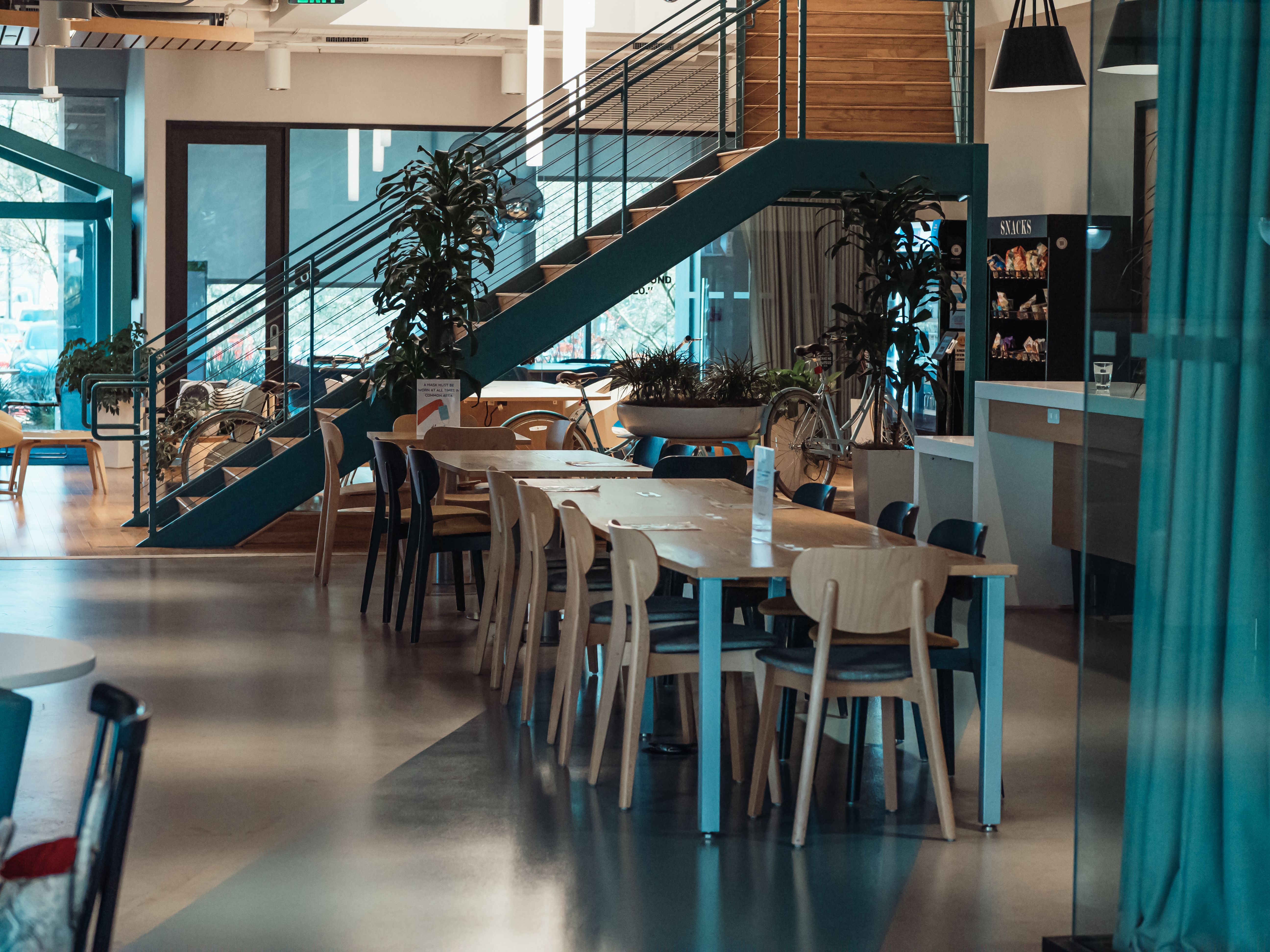 Spacious cafeteria with wooden tables and chairs, showcasing modern design and natural light.